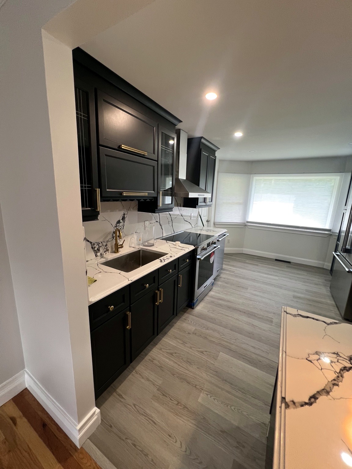 Completed kitchen renovation with dark cabinetry and marble-look backsplash